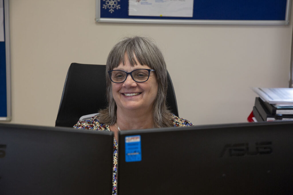 Arrow employee sat at computer smiling